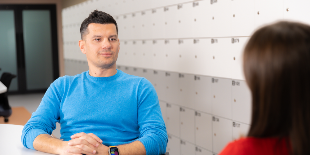 A smiling TaskUs employee in a wheelchair, appearing engaged in his workplace, hinting the vibrant work culture and employee benefits of TaskUs